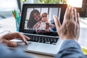 man-waving-and-speaking-on-video-call-with-his-wife-and-child